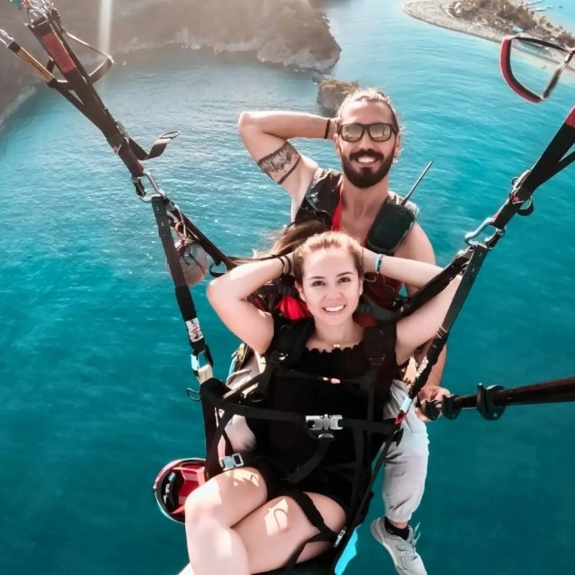 Ölüdeniz'in turkuaz suları üzerinde tandem uçuşta pilot ve yolcu